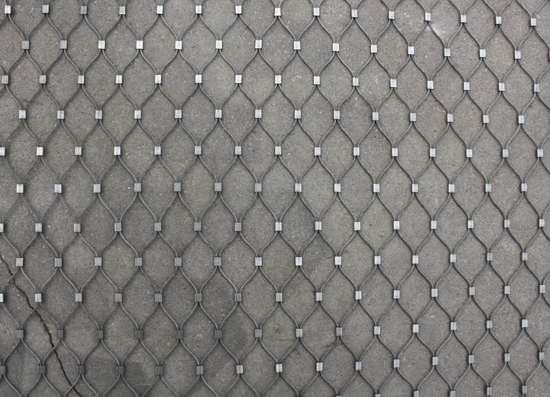 Ferruled stainless steel rope mesh panel fixed flat to a concrete wall in an animal enclosure